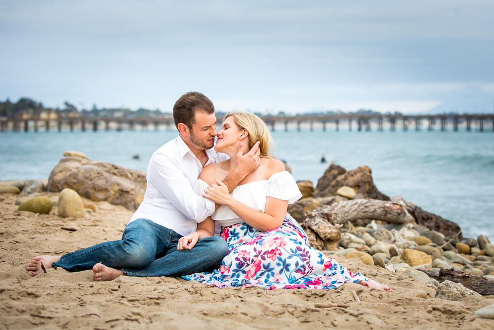 beach engagement photos with man and woman sitting on the beach with each other