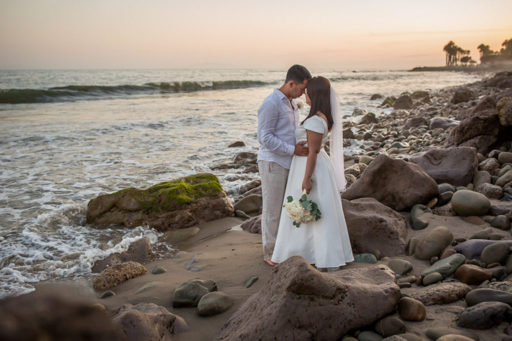 bride and groom on rocky beach sunset