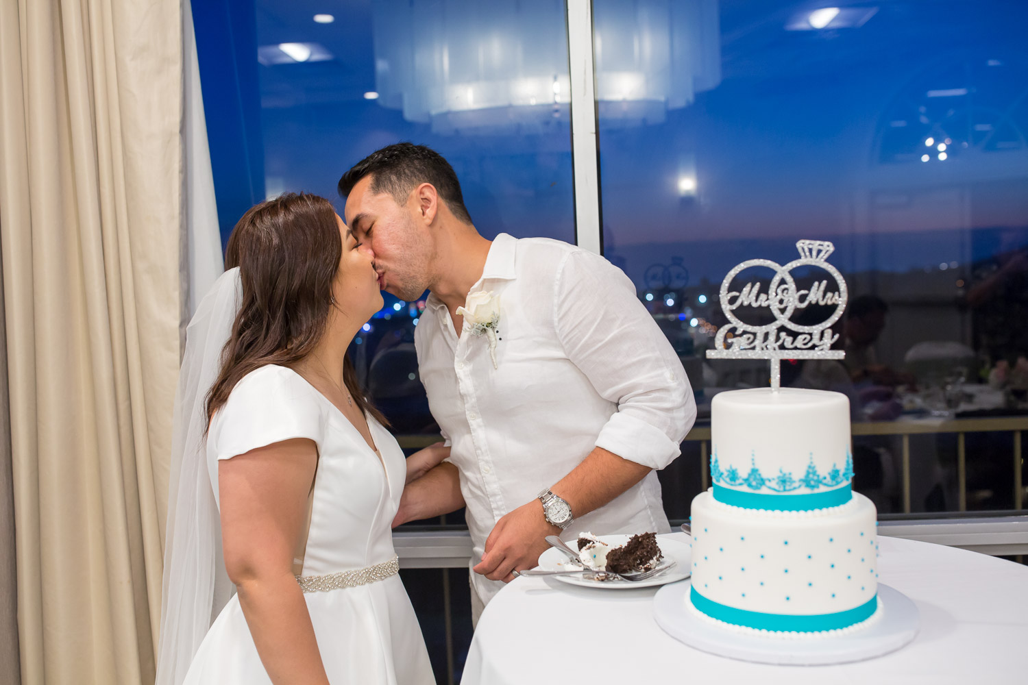 bride and groom kissing by wedding cake