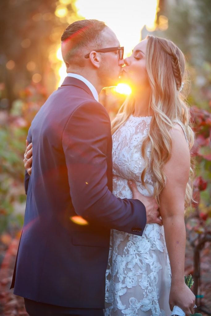 sun setting behind kissing bride and groom