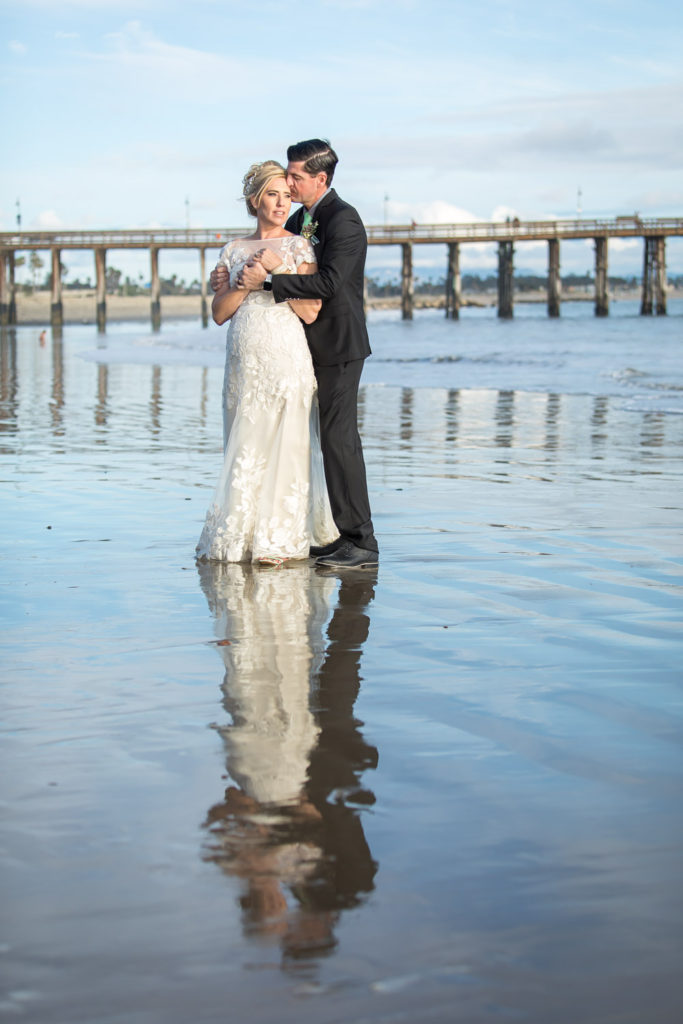 bride and groom standing in the water at the beach in ventura