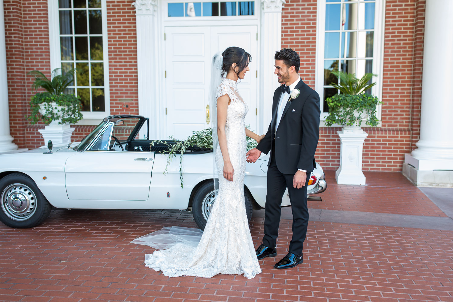 bride and groom standing in front of alfa romera car