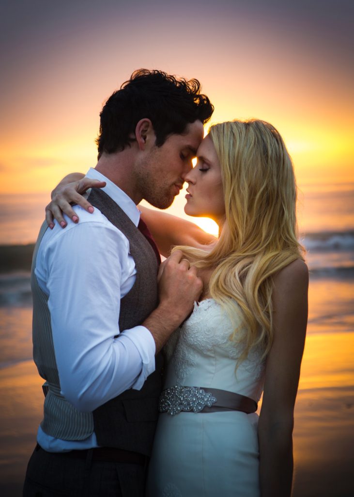 wedding couple kissing with sunset behind them