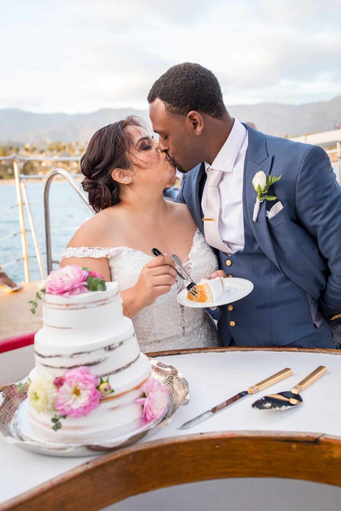 kissing in front of wedding cake Santa Barbara Yacht