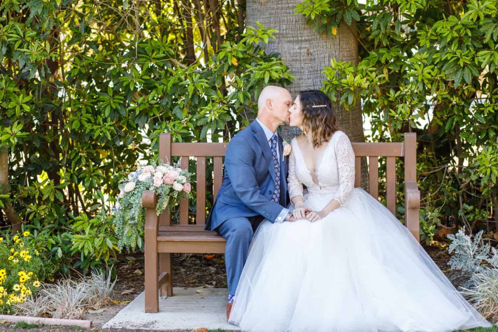 bride and groom sitting on a bench at camarillo ranch
