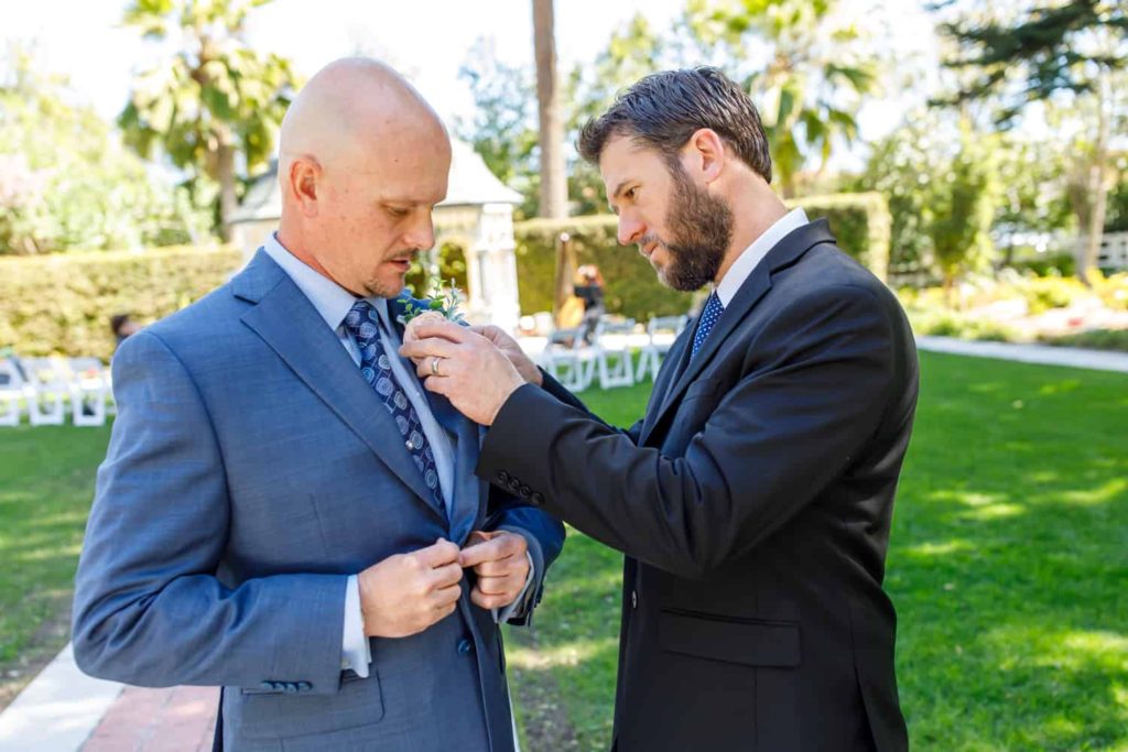 groomsmen putting boutonnière on groom