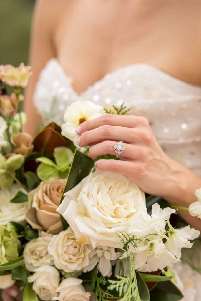 brides hand wearing wedding ring touching bouquet