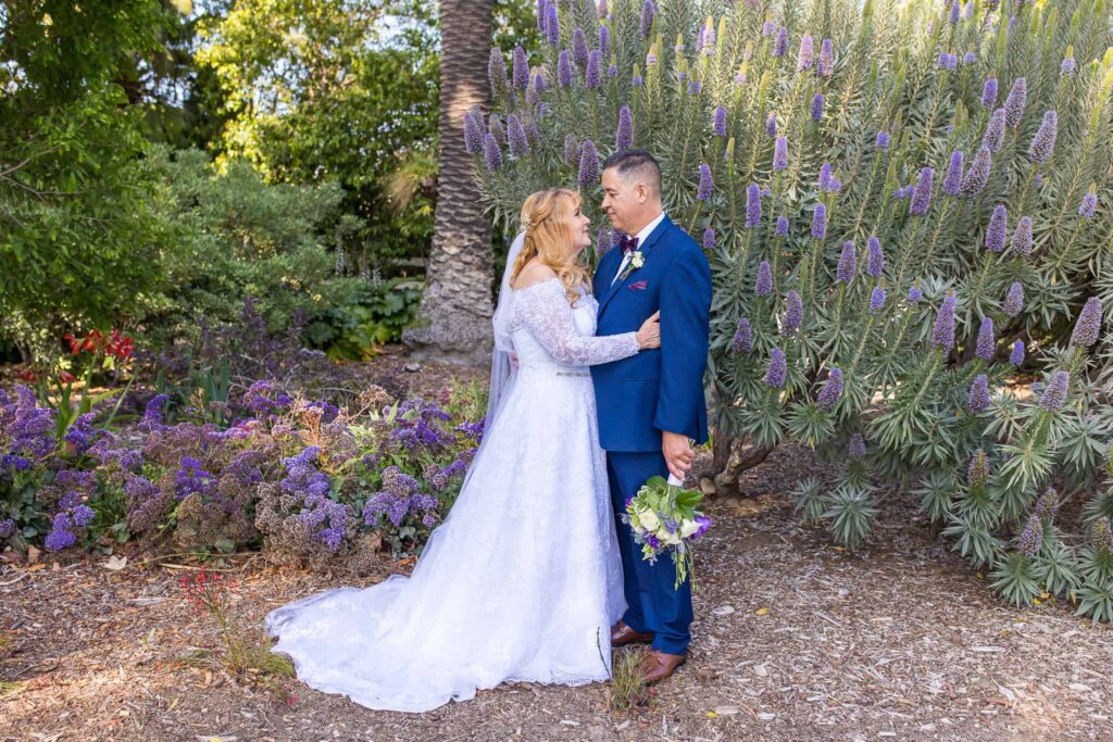 bride and groom by purple flowers