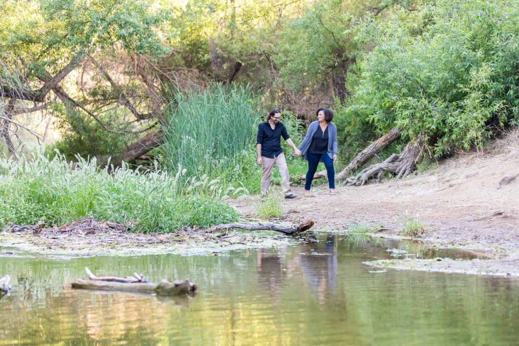 couple walking by creek at their engagement session