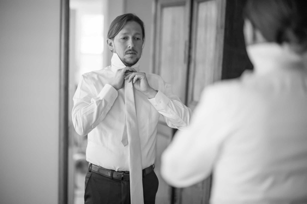 groom adjusting his tie in the mirror in santa barbara