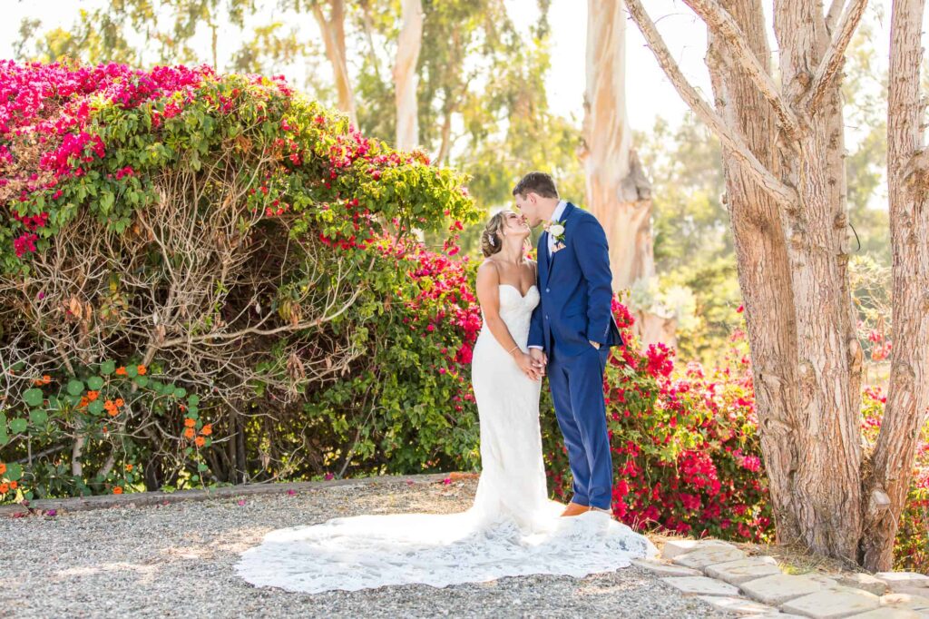 bride and groom kissing surrounded by bouganvillea