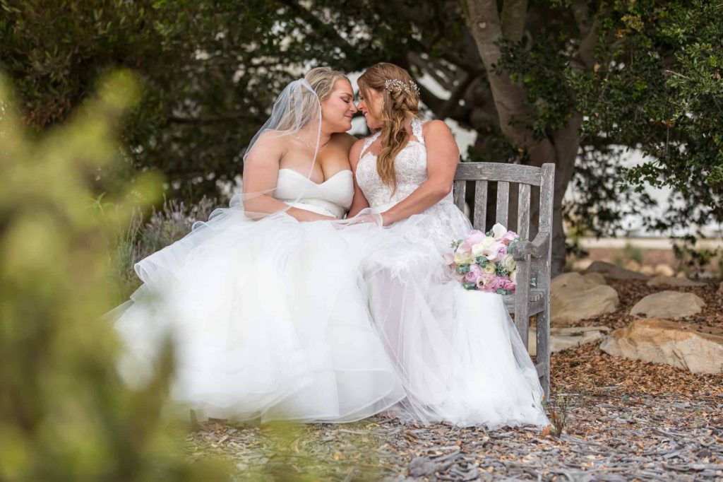 lesbian wedding couple sitting together on a bench