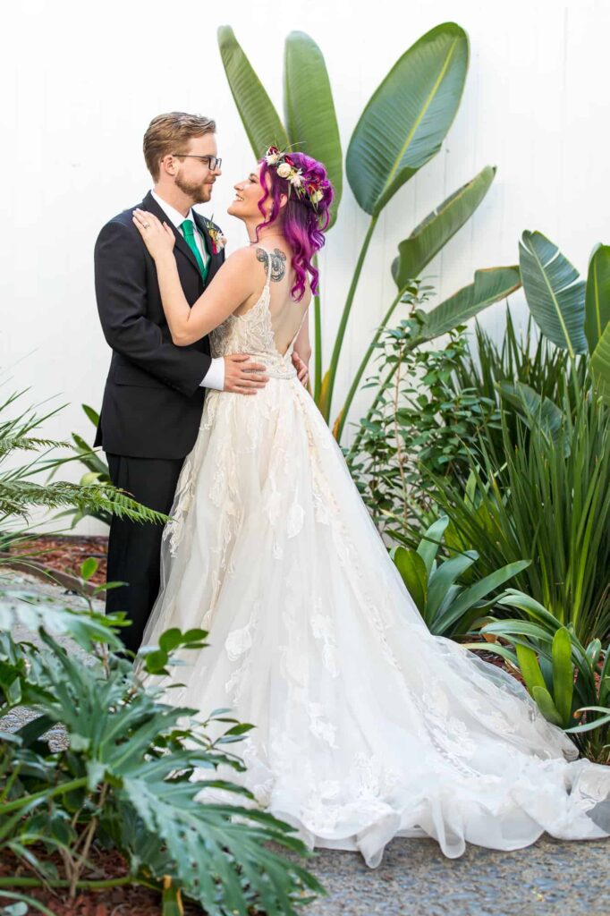 bride and groom looking at each other around tropical plants