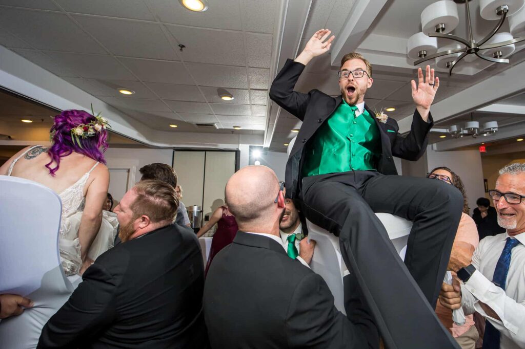 groom being lifted on a chair during reception