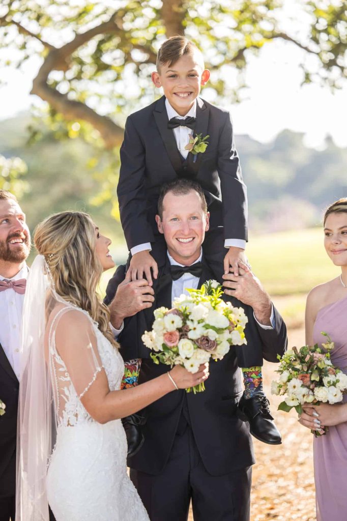 little boy on grooms shoulders at wedding