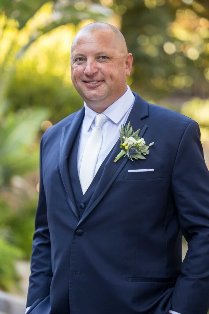 groom with navy suit and white tie