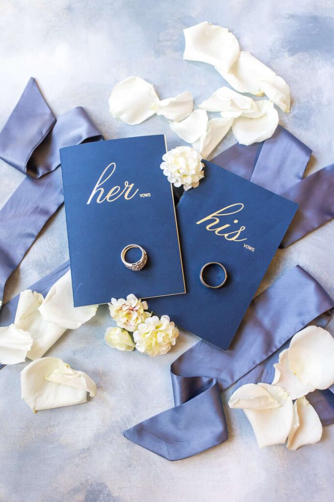 his and her vow books with wedding rings and blue ribbon