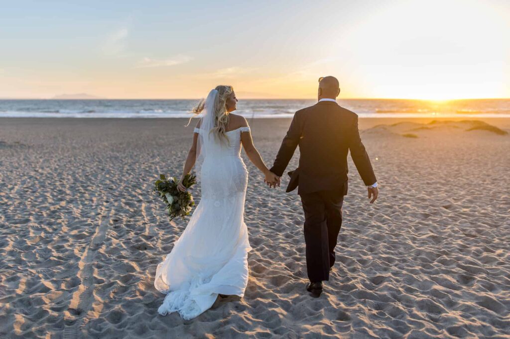bride and groom walking toward the beach