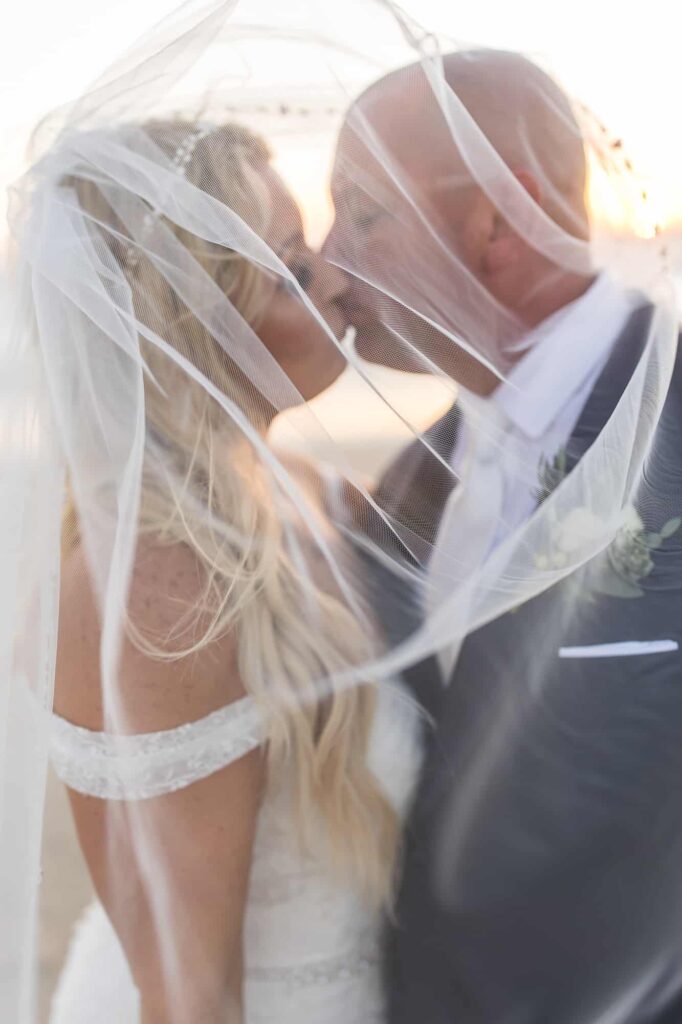 bride and groom under veil kissing