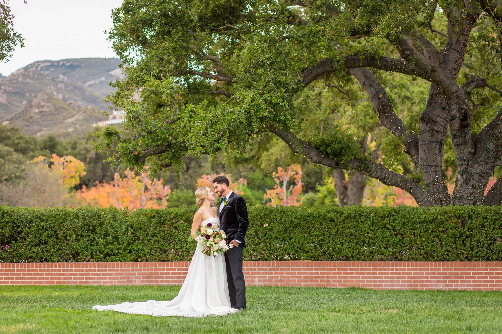 bride and groom standing in a courtyard at their wedding venue with a tree behind them in Ventura County at Sherwood Country Club