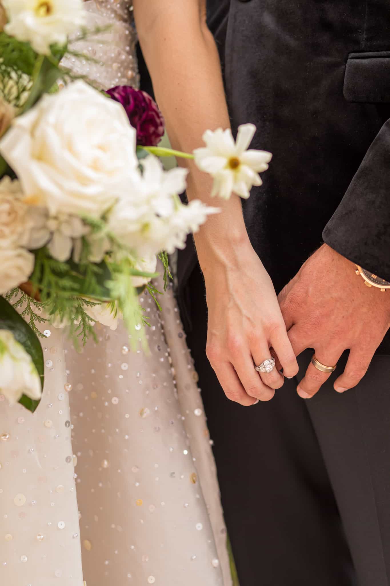 detail shot of bride and groom holding hands together