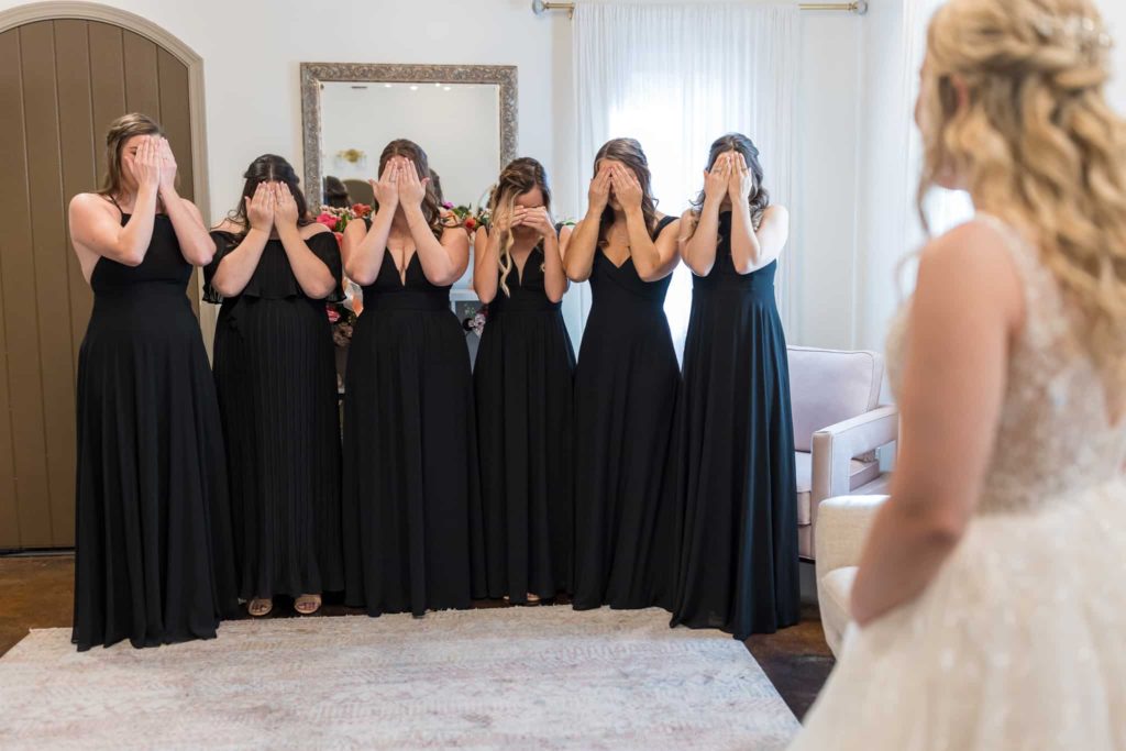 bridesmaids covering their eyes for the first look with the bride