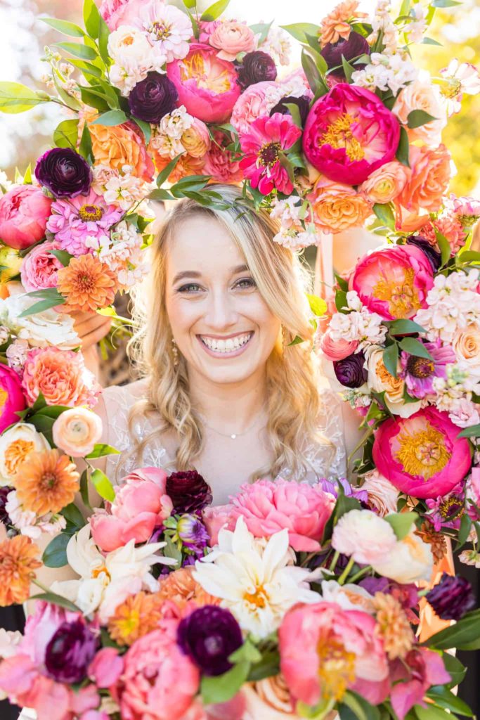 bride surrounded by bright colorful flowers