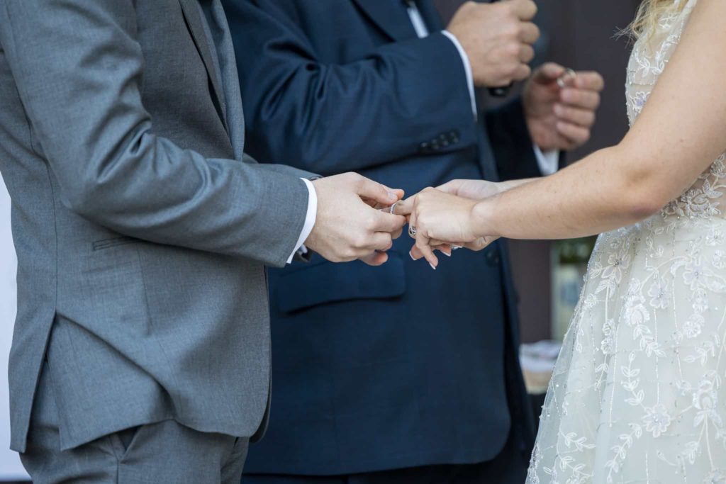 groom putting ring on brides finger during wedding reception