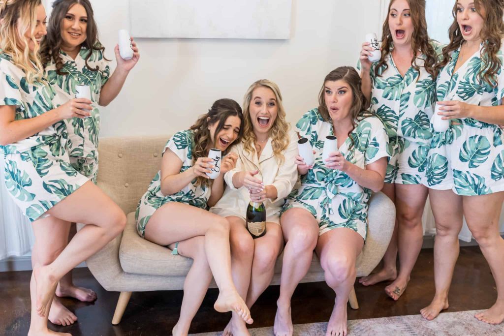 bride popping champagne with her bridesmaids