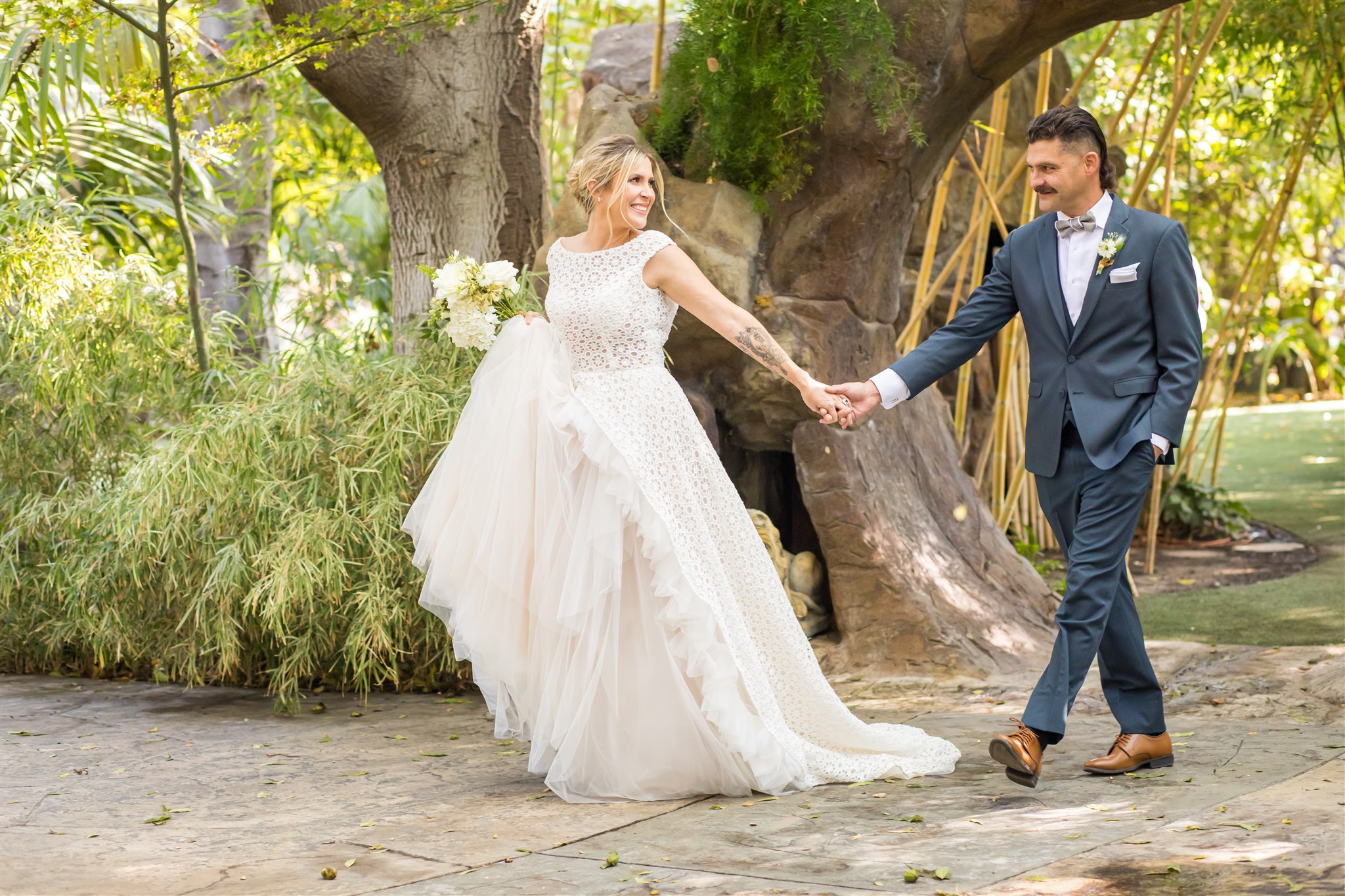 bride and groom holding hands as the bride leads her groom through a stone arch Elope in Santa Barbara: A Guide to a Timeless Elopement