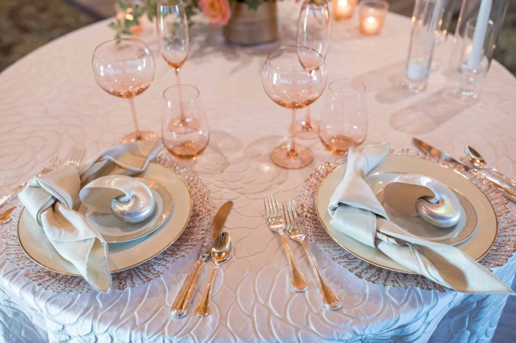 detail shot of classy table settings with silver shells on top of the plates