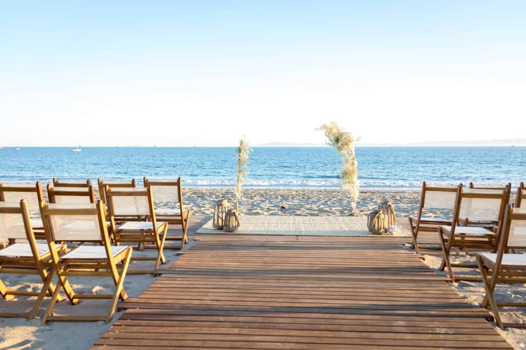 wedding ceremony on the beach with a wood dock leading down the aisle