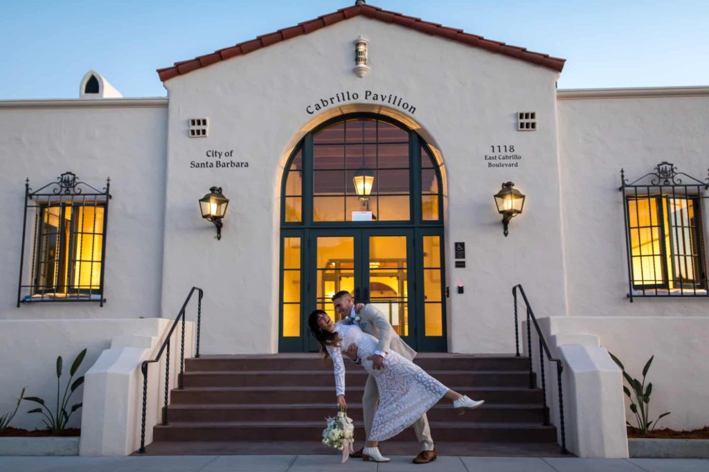 groom dipping his bride backwards in front of their wedding venue Cabrillo Pavilion