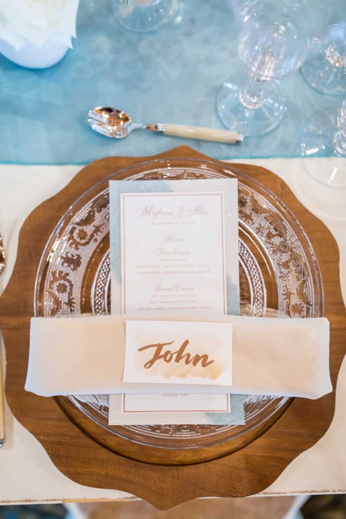 wood platter with crystal dish sitting on top as well as a custom menu for the wedding reception