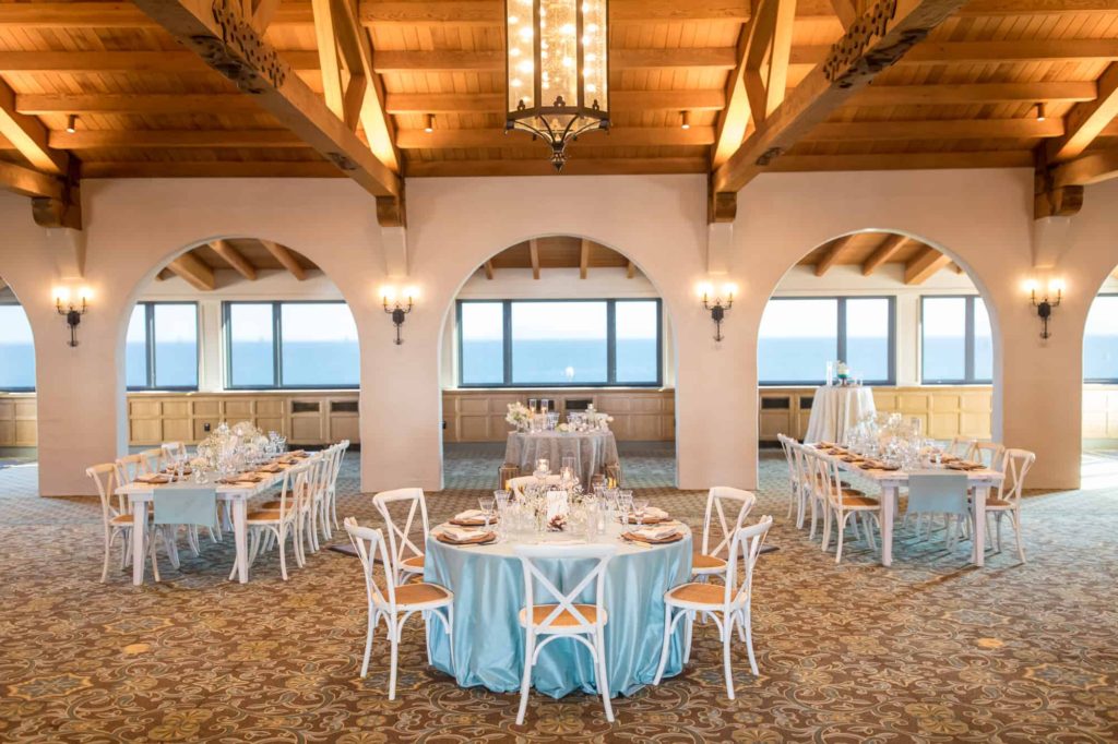 reception space with natural rental white chairs and tables covered in blue table cloths