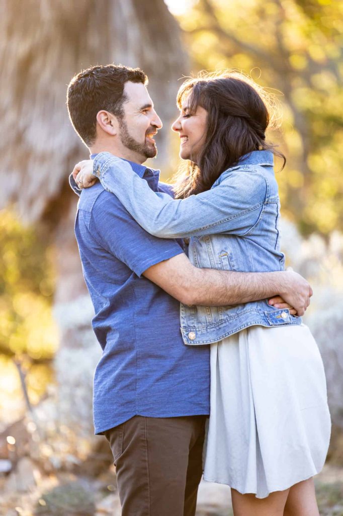 desert engagement photos with man and woman holding each other with the woman arms over his shoulders as she leans into him