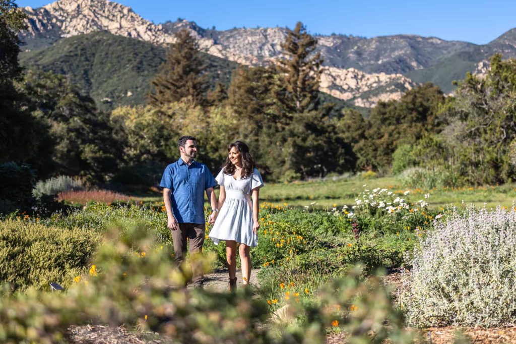 Santa Barbara meadow engagement photos with man and woman holding hands while walking down a path together