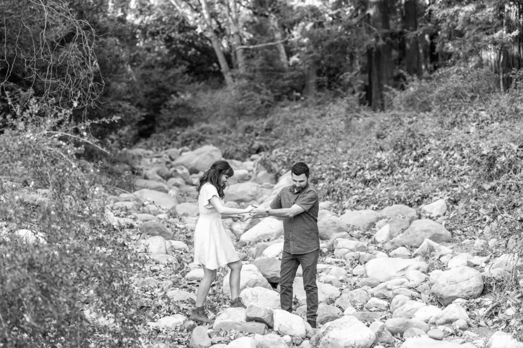 black and white couples photo of man helping woman down into a rock river bed in Botanical Gardens