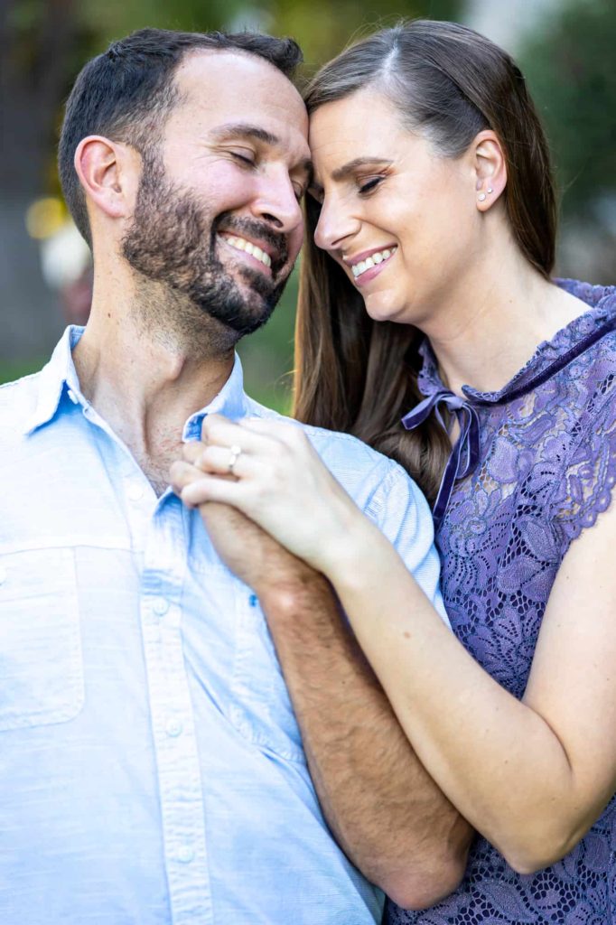 engagement photos with man and woman holding their hands together at their chests while smiling and laughing captured by Santa Barbara wedding photographer
