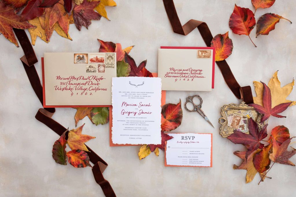 wedding invitations displayed with fall leaves and scissors