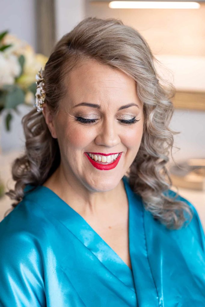 bride looking down and smiling wearing a teal robe