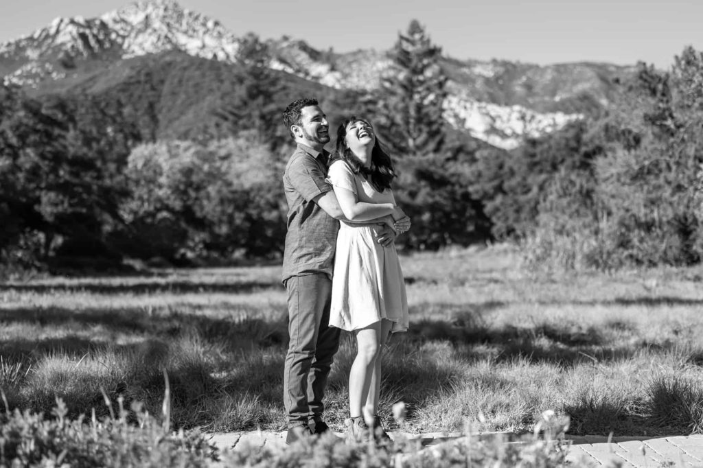 Santa Barbara engagement photos with mountains and a forrest behind the couple as they hold each other and laugh