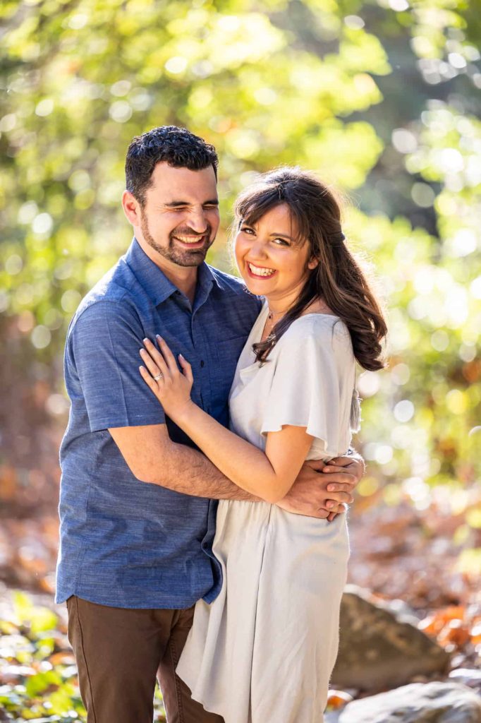 engagement portraits in Santa Barbara with man embracing woman as the sun shines behind them