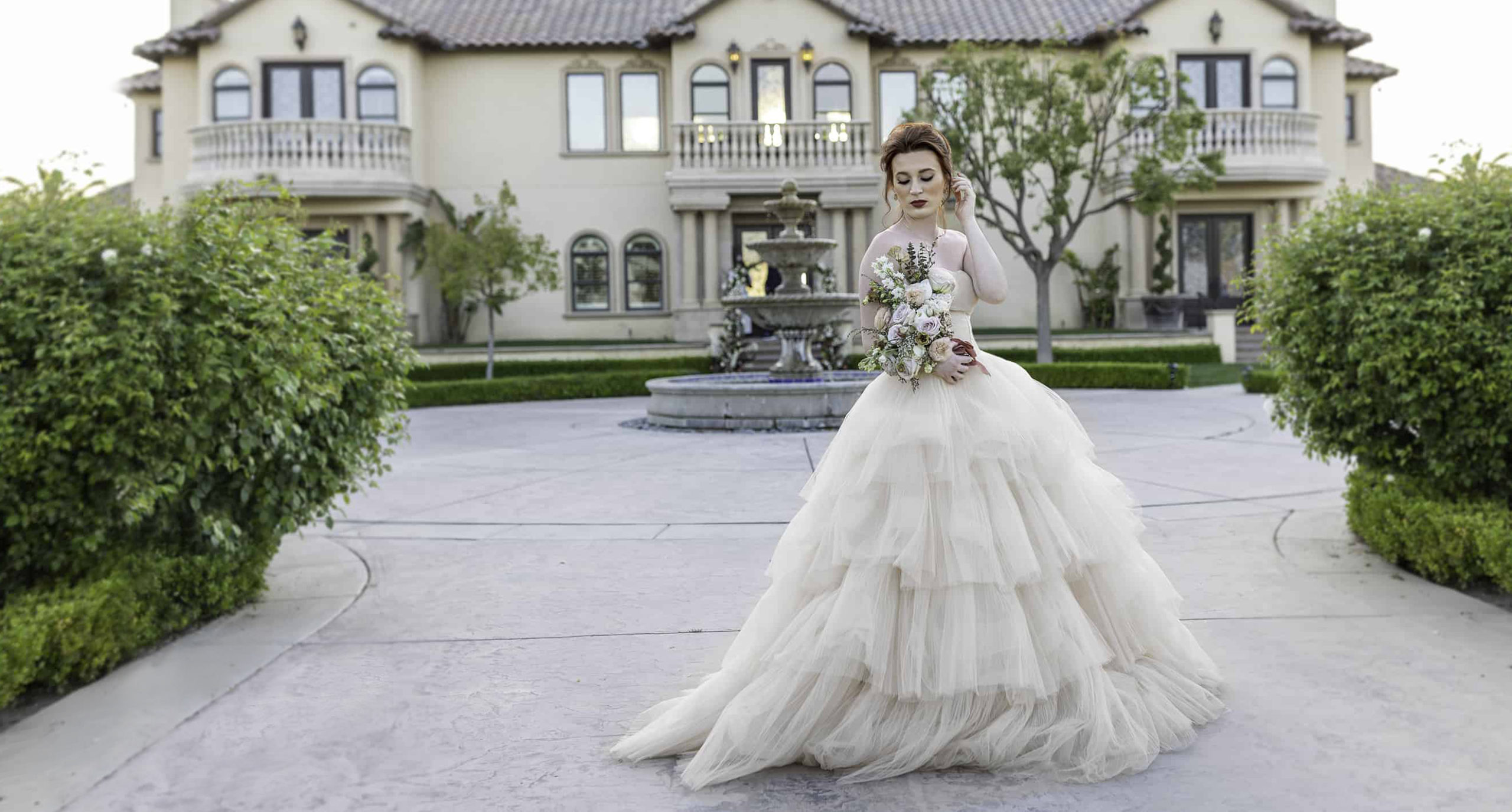 bride in elegant gown with flowers in front of santa barbara villa