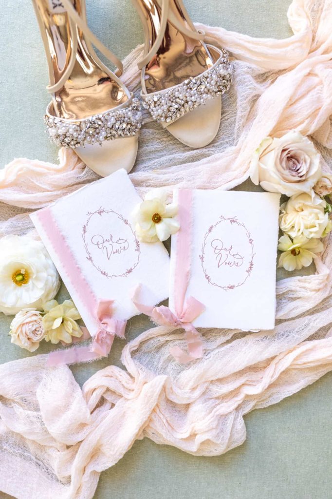 vow books on pink fabric with flowers and shoes