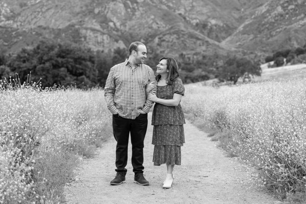 woman holding mans arm as they look at each other kindly for their outdoor California engagement photos