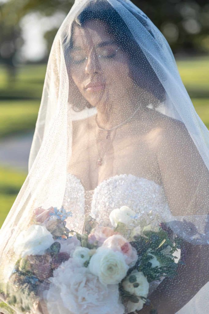 bride with her veil over her head as she holds her bridal bouquet