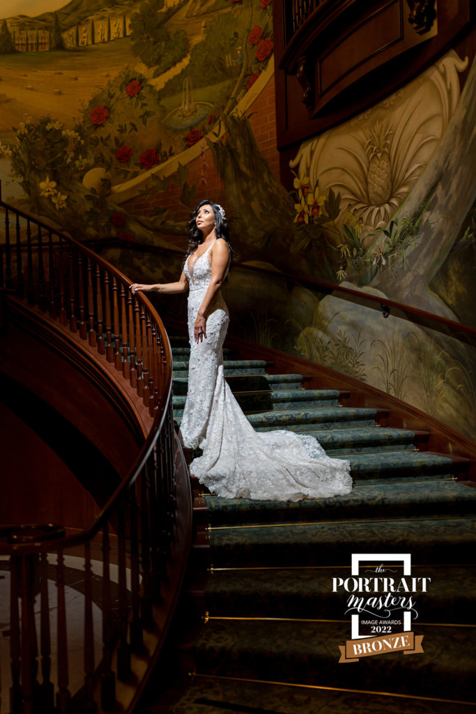 bronze award bride standing on grand staircase with dramatic lighting