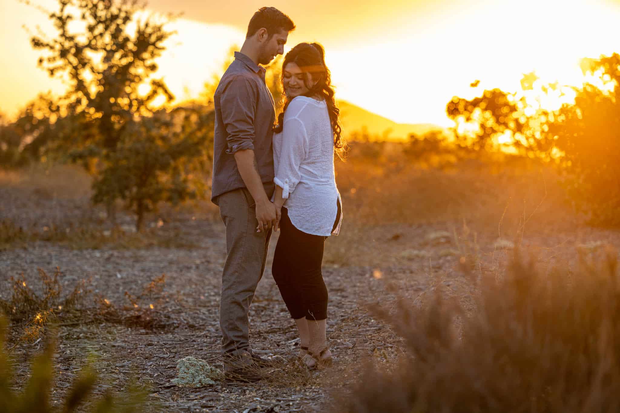 sunset engagement photo in Thousand Oaks with man and woman facing each other and holding hands as the sun sets behind them