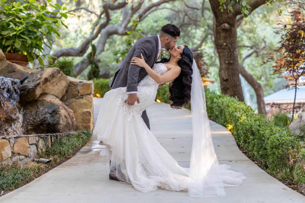 groom dips bride backwards and kisses her in a woodland garden photographed by Los Angeles wedding photographer